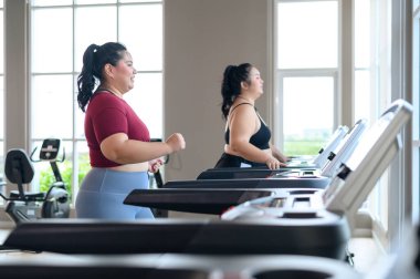 İki güzel, Asyalı şişman kadın spor salonunda koşu bandında birlikte çalışıyor. Kilo verme egzersizi, sağlıklı yaşam tarzı konsepti