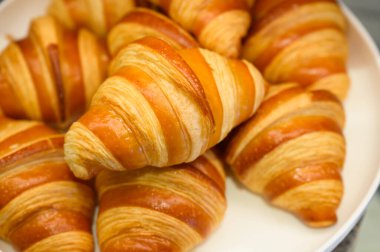 Açık büfede beyaz tabakta ev yapımı mini kruvasanlar. Taze pişmiş tereyağlı kruvasan.