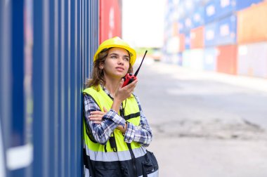 container operators women wearing helmets and safety vests control via walkie-talkie workers in container yards. Cargo Ship Import Export Factory Logistic.