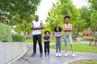 Mutlu Afro-Amerikan gülümseyen aile portresi spor kıyafetleri giyip spor yaptıktan sonra dinleniyor ve eğleniyor. baba, anne ve çocuk