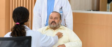 Yaşlı hasta adam tekerlekli sandalyede otururken genç bayan doktor kalp atışlarını kontrol etmek için steteskop kullanıyor, yaşlı sağlık kontrolü, mutluluk hastanesi.