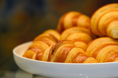 Açık büfede beyaz tabakta ev yapımı mini kruvasanlar. Taze pişmiş tereyağlı kruvasan.