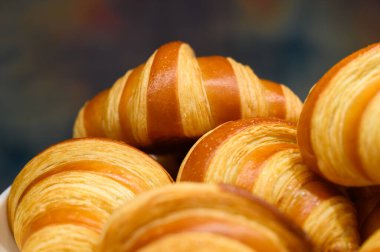 Açık büfede beyaz tabakta ev yapımı mini kruvasanlar. Taze pişmiş tereyağlı kruvasan.