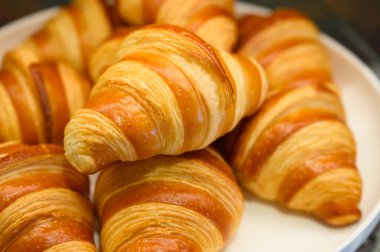 Açık büfede beyaz tabakta ev yapımı mini kruvasanlar. Taze pişmiş tereyağlı kruvasan.