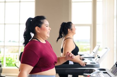 İki güzel, Asyalı şişman kadın spor salonunda koşu bandında birlikte çalışıyor. Kilo verme egzersizi, sağlıklı yaşam tarzı konsepti