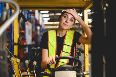 İşinden bezmiş çalışanlar. Kadın forklift sürücüsü depoda çalışmaktan yorgun düşmüş.