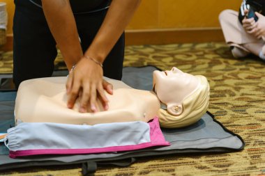 CPR First Aid Training with CPR dummy in the class. Demonstrating chest compressions concept