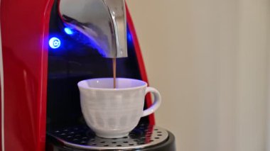 Siyah kahve kapsüllü otomatik kahve makinesi ya da kahve kapsülleri seramik beyaz fincana espresso dolduruyor.