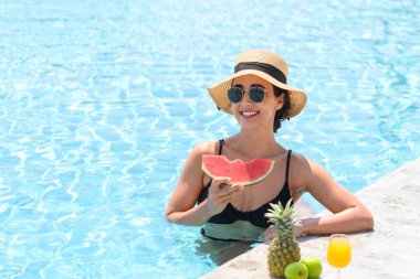 Havuzda hasır şapkalı, bikinili mutlu kadın dinleniyor. Güzel dişiler karpuz yer. Yaz zamanı. tatil kavramı