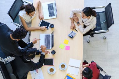 Modern ofisteki en geniş görüşlü bilgisayarlarla iş adamları grup toplantısı. Başarılı iş adamları iş arkadaşlarıyla birlikte çalışırken analitik rapor