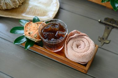 Hoş geldin içkisi. Soğuk havluyla buzlu Bael Suyu ve kuru Bael Ahşap tepside ıssız