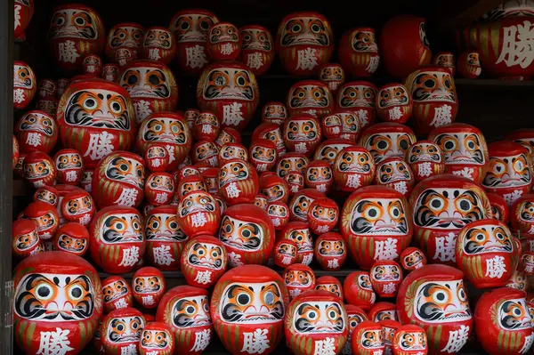 Japonya 'nın Minoh, Osaka kentindeki Katsuo-ji tapınağındaki ahşap rafta yığınla kırmızı Daruma bebeği var. Kanji İngilizceye çevrildi: 