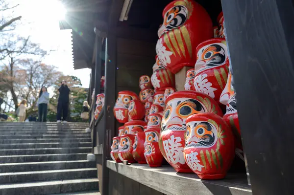 Japonya 'nın Minoh, Osaka kentindeki Katsuo-ji tapınağındaki ahşap rafta yığınla kırmızı Daruma bebeği var. Kanji İngilizceye çevrildi: 