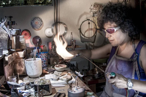 Kuyumcu kadın atölyesindeki meşaleyi kullanıyor.