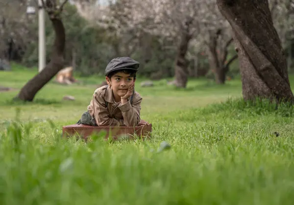 Parkta yaslanmış çocuk konsantre görünüyor.