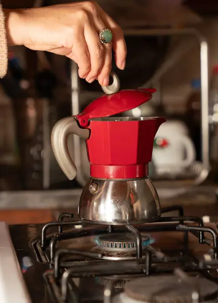 Elinde kırmızı bir İtalyan moka kabı var.