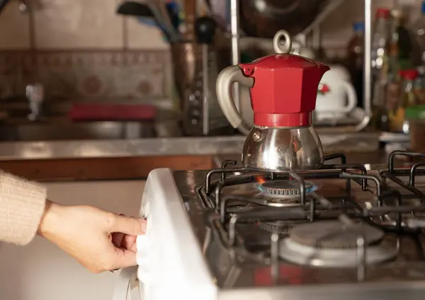 El, ocak ateşini moka tenceresiyle ayarlıyor.