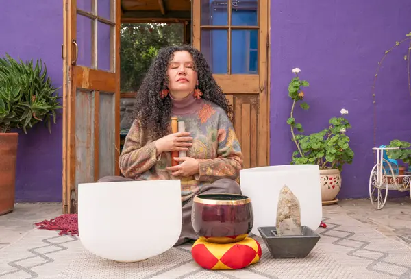 Tibet şarkı kaseleriyle huzur dolu bir bahçede meditasyon yapan bir kadın.