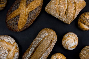 Different types of freshly baked bread on a black background. View from above.