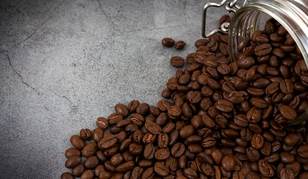 暗い石の背景に散在する焙煎コーヒー豆 — ストック写真