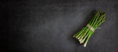 Koyu taştan bir zemin üzerinde yeşil kuşkonmaz, boşluğu kopyala.