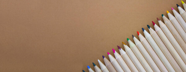 Wooden pencils on a light brown background. Back to school. Banner