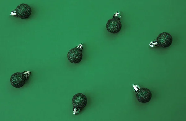 Green Christmas balls on a green background. Festive background, copy space.