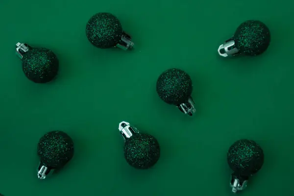 Green Christmas balls on a green background, close up. Festive background.