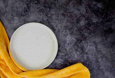 Beyaz tabak, gri arka planda sarı peçete, metin için yer