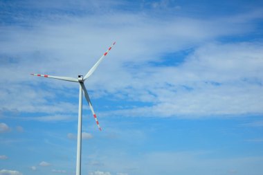 Rüzgar türbini parlak, güneşli bir gökyüzünün altında yenilenebilir enerji üretir..