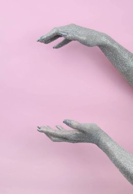 Parıldayan eller zarif bir şekilde pembeye karşı sanatsal bir ifade sergiliyor..