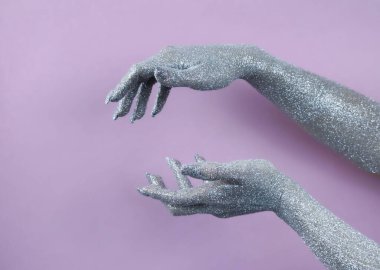 Pırıl pırıl parlayan eller zarif bir jest yumuşak pembe bir arka plana karşı, sanatsal sergilenen.