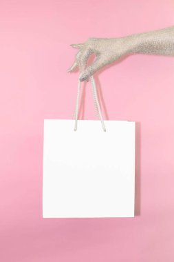 Işıl ışıl bir el, canlı pembe bir zemin üzerinde boş bir alışveriş çantası sunar. Markalaşmak için mükemmeldir..