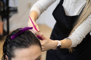 Stylist uses scissors and a comb to create a new hairstyle for a client. clipart