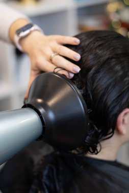 Bir stilist, saç üzerinde profesyonel bir araç kullanırken bir tedavi uygular.