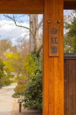 Tahta bir kapı ziyaretçileri yeşilliklerle bezenmiş sakin bir bahçeye buyur eder..