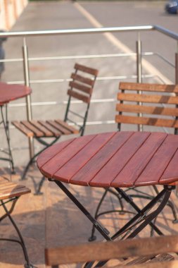 Tahta masalar ve sandalyeler gün ışığında sessiz bir açık alanda dizilmiş..