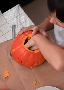 A child carves a pumpkin for Halloween, enjoying the festive spirit.