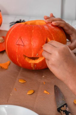 Hands skillfully carving a spooky face on a pumpkin