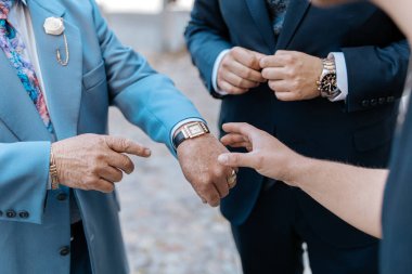 Zarif takım elbiseli bir adam saatini gösteriyor.