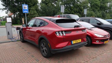 Elburg, Hollanda - 23 Eylül 2022 Kırmızı bir Ford Mach-E park etti. Araba Hollanda 'da büyük bir otoparkta şarj ediliyor.