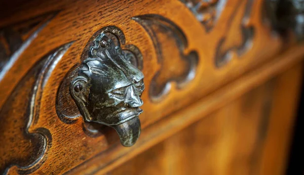 Drawer handles in the shape of a devil. Detail of an old Dutch cupboard
