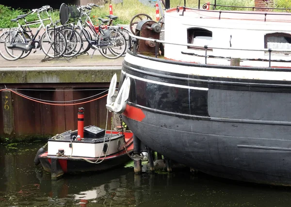 Amersfoort, Hollanda - 23 Temmuz 2016 Büyük bir geminin rıhtımına küçük bir tekne yanaştı. Rıhtımda bisiklet dolu bir bisiklet parkı var.