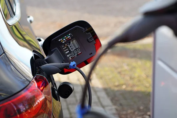 Charging an electric car. In the background is the plug connected to the car. The plug that is connected to the charging station is blurred.