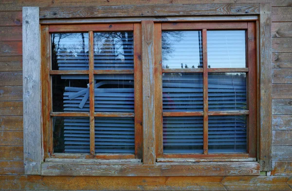 A window in a garden shed with broken blinds. The stained wood has also seen better days