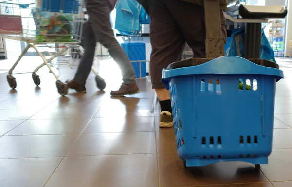 Ноги Человека Который Делает Покупки Тянет Синюю Пластиковую Корзину Покупок — стоковое фото