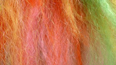 Horizontal picture of fluffy wool-like threads in the colours orange, yellow, pink and green clipart