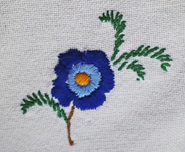 Embroidery blue flower with leaves on white background.