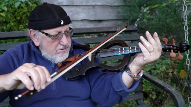 Sessiz bir kemanla liman şapkalı bir adam çalıyor.