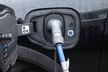 Elektrikli bir araba şarj edilir. Fiş arabanın prizine takılıyor. 